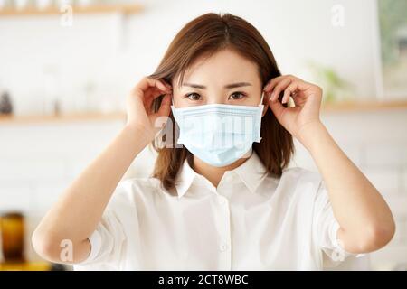 beautiful young asian woman putting on a mask on face Stock Photo