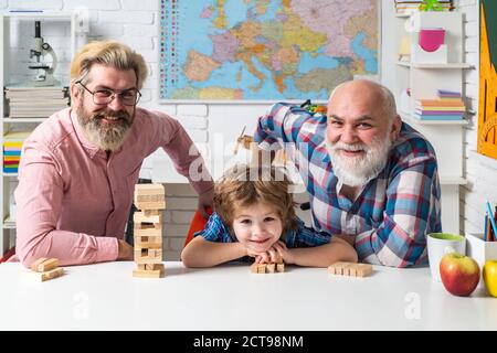 Three generations of active men playing in living room. Jenga game at home. Stock Photo