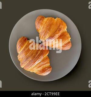 two fresh croissants on grey plate, top view Stock Photo
