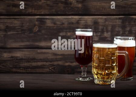 Various sorts of draft beer in glasses and mug on wooden table, copy space. Fresh brewed beer. Stock Photo