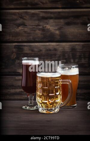 Various sorts of draft beer in glasses and mug on wooden table, copy space. Fresh brewed beer. Stock Photo