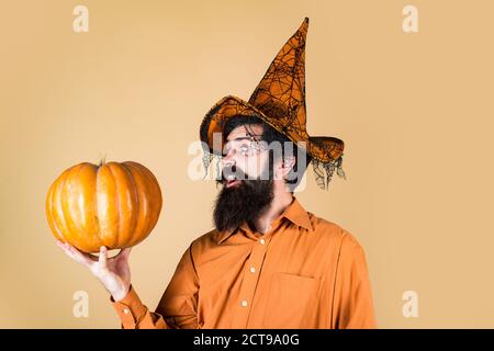Young man with witch hat ready to Halloween party. Trick or treat. Bearded man cook in Halloween hat with pumpkin. Devil man. Celebrating happy Stock Photo