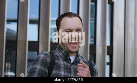 Young man looking at camera seriously and starts laughing. Stock Photo