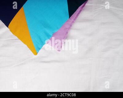 Colorful pillows, decorative pillows pink and blue on a white bedspread against a brick wall. Comfort and convenience at home Stock Photo