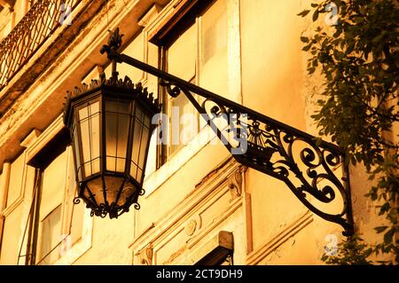 Lantern with Lisbon symbol (ship with two ravens) on the old building in the centre of Lisbon (Portugal). Golden sunset light. Toned photo. Stock Photo