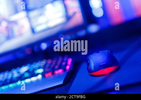 Professional computer mouse for video games and cyber sports on background of monitor, neon color Stock Photo