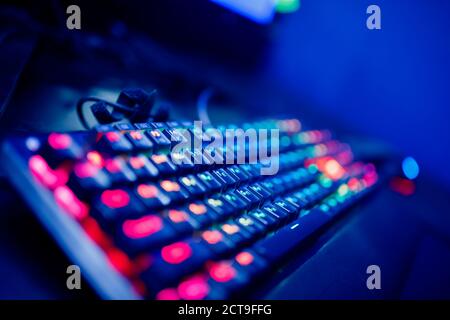 Professional cyber video gamer studio room with personal computer armchair, keyboard for stream in neon color blur background. Soft focus Stock Photo