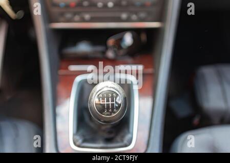 horizontal close up high angle image of a black and white manual car gear stick with the gearbox in a blurry background Stock Photo