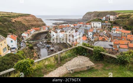 Multiple image panorama of a bench looking down on pretty fishing village of Staithes on the North Yorkshire coast seen in September 2020. Stock Photo
