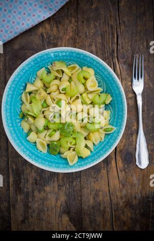 Plate of noodle salad with avocado, peas and celery on wood, elevated view Stock Photo