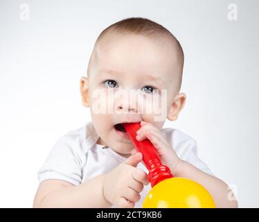 Photo of a eleven-month-old baby with rattle in mouth Stock Photo