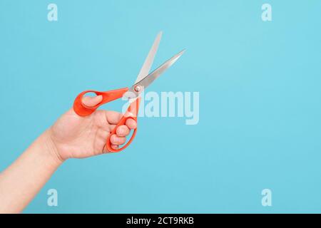 scissors in hands on blue background Stock Photo