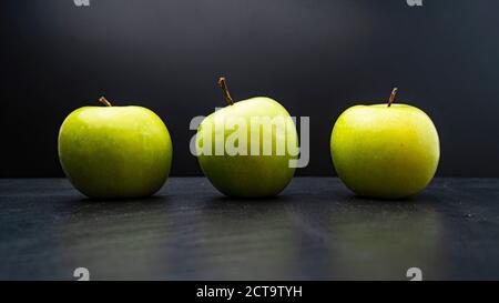 Three ripe fresh green apples isolated on black background. Free copy space. School snacks or organic food concept Stock Photo