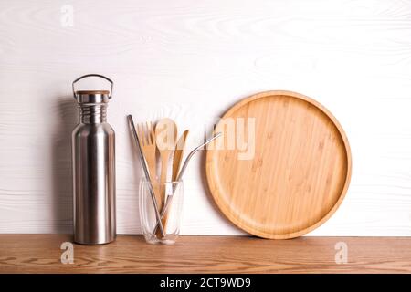 Eco set with bamboo cutlery, reusable water bottle on wooden background. Stock Photo