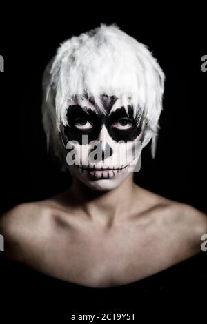 Portrait of woman with skull make-up wearing headgear of white feathers, studio-shot Stock Photo