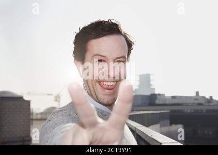 Portrait of smiling man showing victory sign Stock Photo