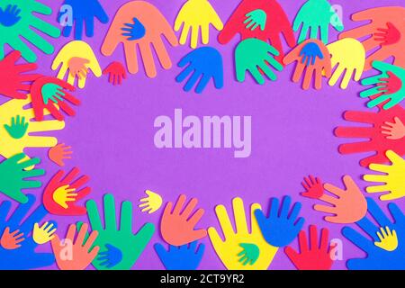 Colorful red, orange, yellow, green and blue foam hands of different sizes on a plain purple background Stock Photo