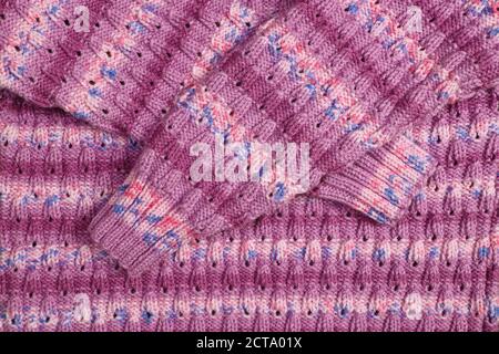 Abstract textured background of close up detail of the pattern in a pink hand knitted jumper Stock Photo