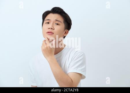 Young handsome man over white background looking confident at the camera smiling with hand raised on chin. Thinking positive. Stock Photo