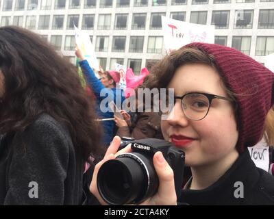 01/21/2017 Washington DC, USA: Women's March - Young female photographer marches in mass demonstration surrounded by activists. Stock Photo