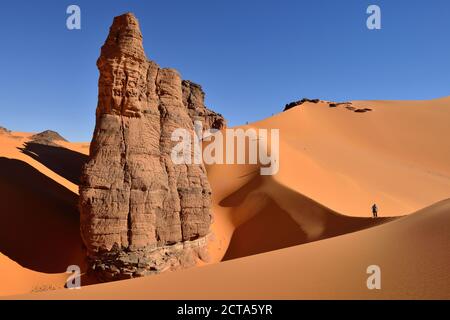 Algeria, Tassili n' Ajjer, Tadrart, Sahara, Tassili n' Ajjer National Park, view to sand dunes and rocks of Moul Nag with people at background Stock Photo
