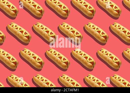 Fast food for company. Appetizing hot dogs with sausage and mustard on pink background Stock Photo