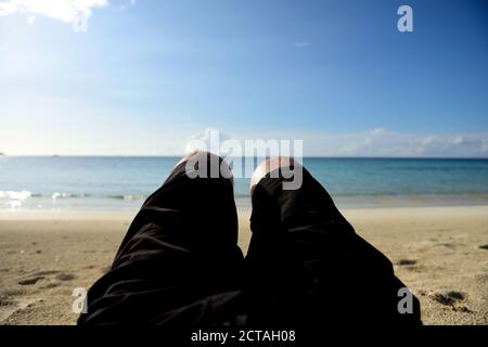 Point of view of man relaxing on deserted Caribbean island beach with blue water ocean, blurred background Stock Photo