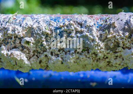 Dirty blue painted metal pipes stained with pieces of cement. Peeling paint and concrete texture on metal pole Stock Photo