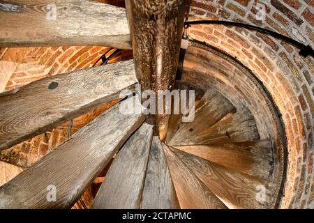 Looking down an old wooden spiral staircase in a brick circular turret in an old medieval brick church tower. Stock Photo