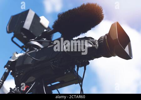 Video camera - Ready for recording show in outdoor TV studio - focus on camera aperture Stock Photo