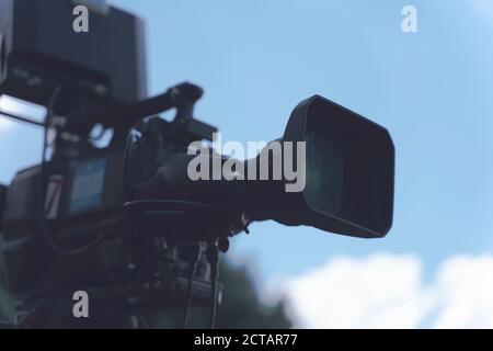 Video camera - Ready for recording show in outdoor TV studio - focus on camera aperture Stock Photo