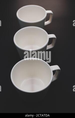Vertical shot of three empty cups on a black surface Stock Photo