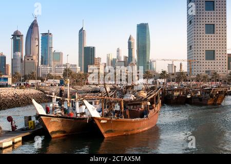 Arabic traditional wooden dhows in front of Kuwait skyscrapers in the beautiful evening light. Middle East, Kuwait City. Al Hamra Tower Stock Photo