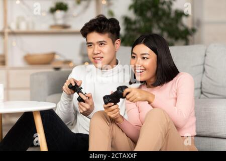 Chinese Girlfriend And Boyfriend Playing Videogame Using Games Console  Sitting On Floor At Home. Computer Gaming And Videogames For Couple, Family  Weekend Leisure Concept Stock Photo, Picture and Royalty Free Image. Image