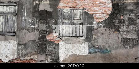 Abandoned brick wall texture of ancient house, abstract rough, cracked, eroded, damaged plaster and old wooden window. Full frame. Stock Photo