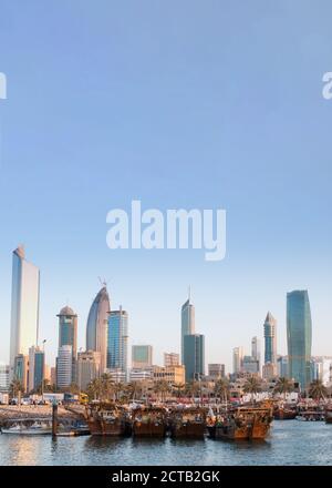 Arabic traditional wooden dhows in front of Kuwait skyscrapers in the beautiful evening light. Copy Space. Stock Photo