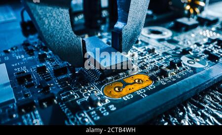Macro Close-up Shot of Factory Machine at Work: Printed Circuit Board Being Assembled with Robotic Arm, Surface Mounted Technology Connecting Microchi Stock Photo