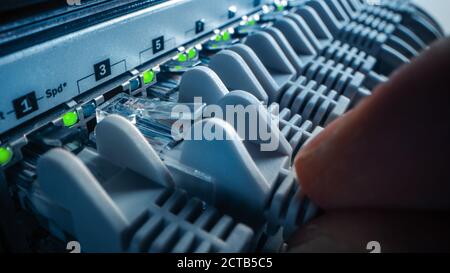 Macro Shot: Person Plugs in RJ45 Internet Connector into LAN Router Switch. Information Communication Network with Data Cables Connected to Modem Port Stock Photo