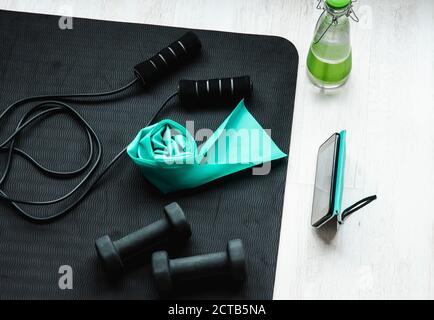 Online training class concept. Video from smartphone screen. Top view of home workout equipment, jumping rope,  resistance exercise latex rubber band, Stock Photo
