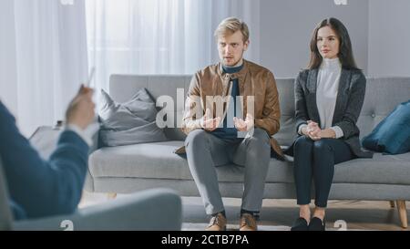 Young Couple on Counseling Session with Psychotherapist. Back View of Therapist Taking Notes: Angry Boyfriend loses Temper. Domestic Violence Stock Photo
