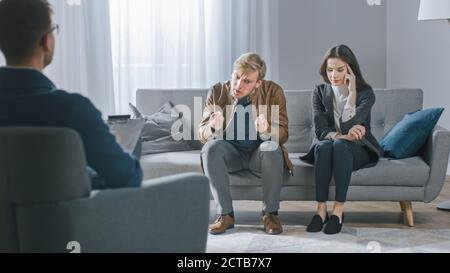 Young Couple on Counseling Session with Psychotherapist. Back View of Therapist Taking Notes: Angry Boyfriend loses Temper, Starts to Shout at His Stock Photo