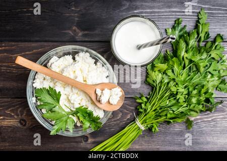 Fresh plain homemade yougurt and cottage cheese yogurt, youghurt, kefir, ayran, lassi in glass with herbs over wooden background, copy space Probiotic Stock Photo