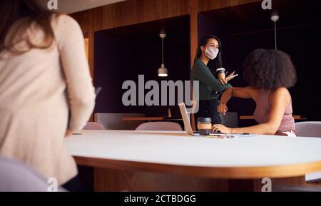 Businesswomen Wearing Masks Having Socially Distanced Meeting In Office During Health Pandemic Stock Photo