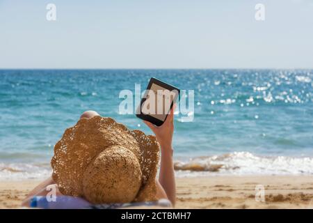 Woman relaxes while reading on the beach Stock Photo