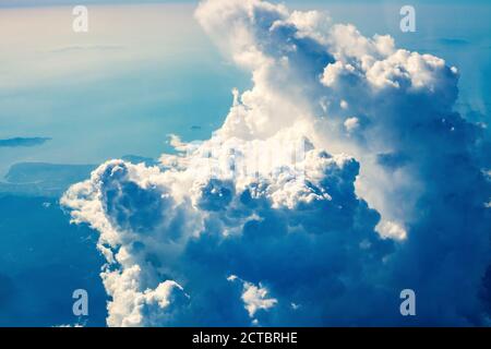 Cumulus huge storm clouds in blue sky at sunny light day. Beauty spring landscape with cloudy skyline, top view from flying airplane window Stock Photo