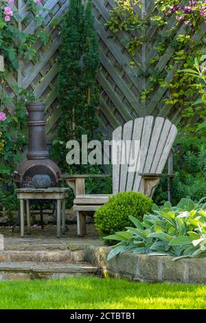 Landscaped, private garden close-up (contemporary design, border & climbing plants, fence, patio furniture seat & chiminea) - Yorkshire, England, UK. Stock Photo