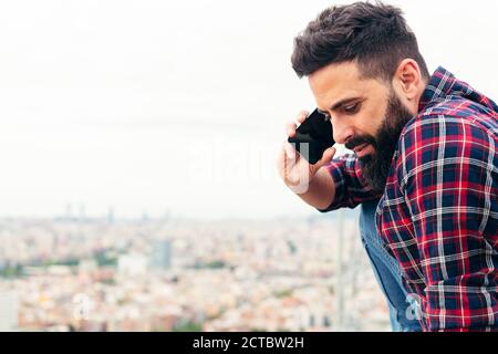 portrait of a handsome bearded man making a call on his mobile phone, concept of freedom and technology, copy space for text Stock Photo