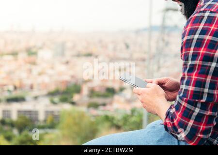detail of the hands of a seated man consulting the mobile phone, concept of freedom and technology, copy space for text Stock Photo