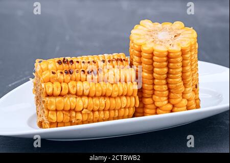 Freshly cooked organic ear of corn with kernels on white plate close-up Stock Photo