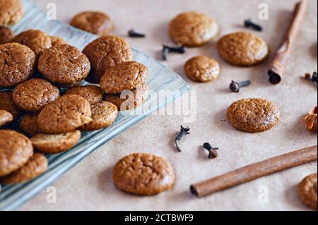 Prepared traditional seasonal round ginger cookies with cloves and cinnamon spices on plate and cooking paper Stock Photo